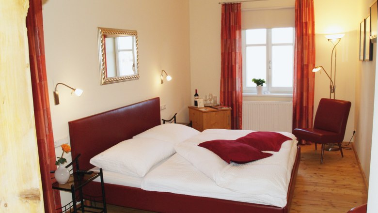 Gemütliches Schlafzimmer mit rotem Bett und Dekor.