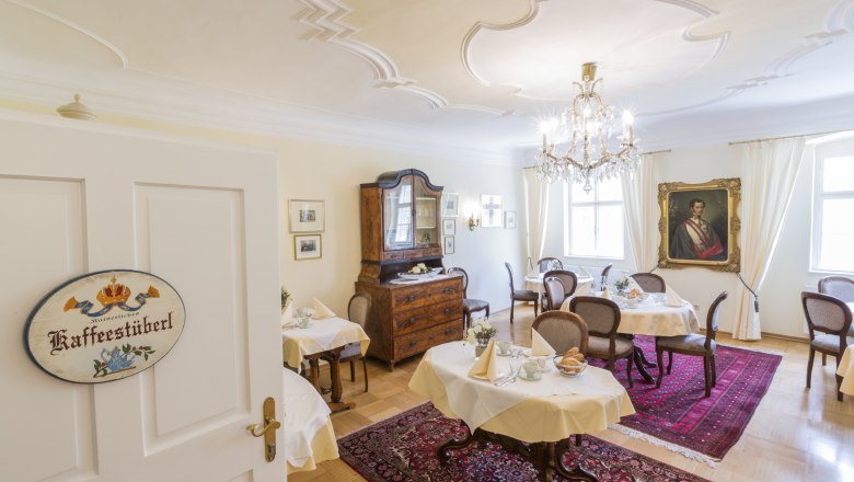 Elegantes Café im Barockstil mit Kronleuchter, antiken Möbeln und Gemälde an der Wand.