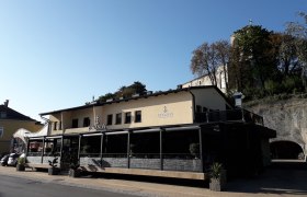 Gebäude mit der Aufschrift 'Bevanda' und Terrasse, umgeben von Bäumen und Felsen.