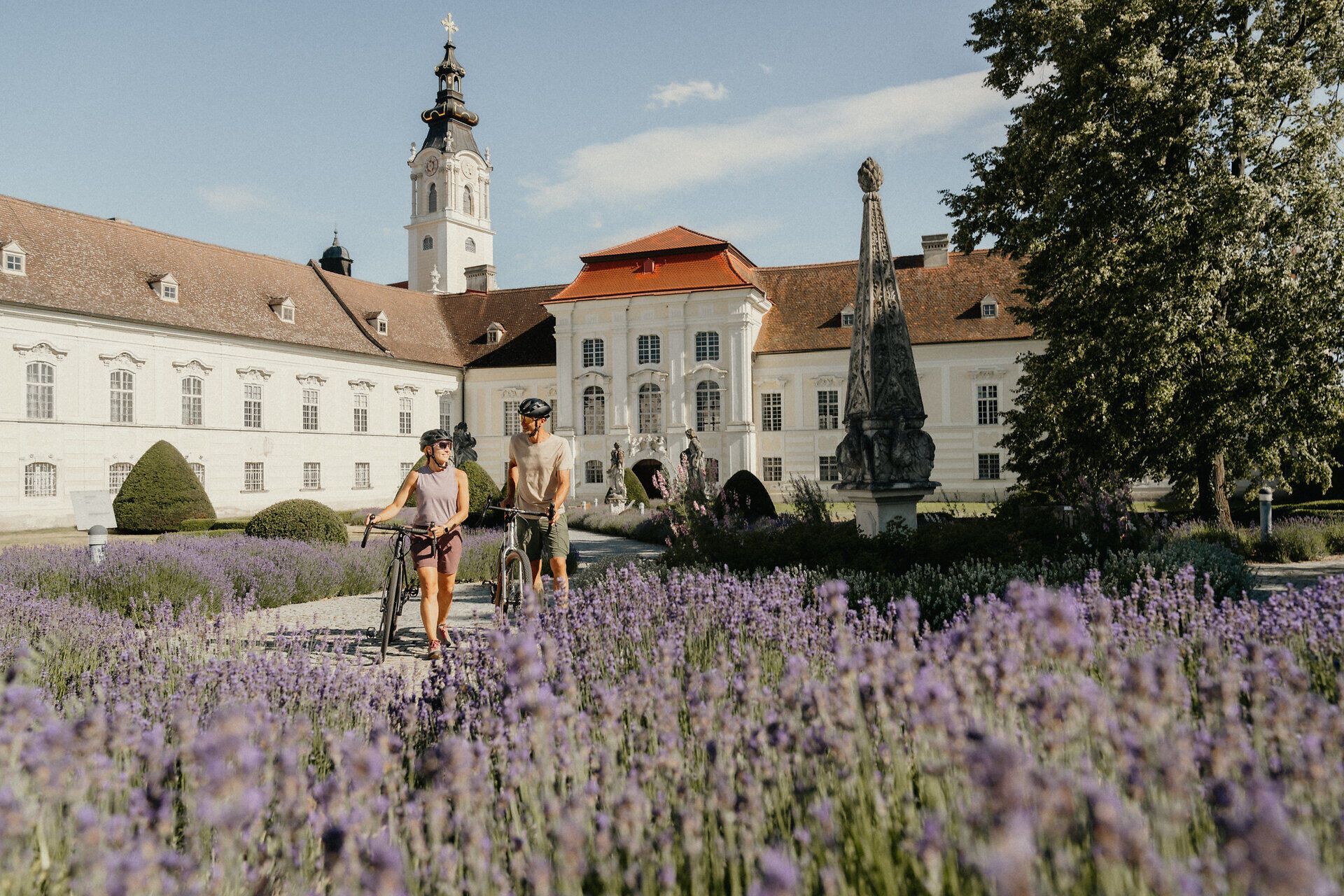 Barockes Stift mit Garten und Statuen im Vordergrund.