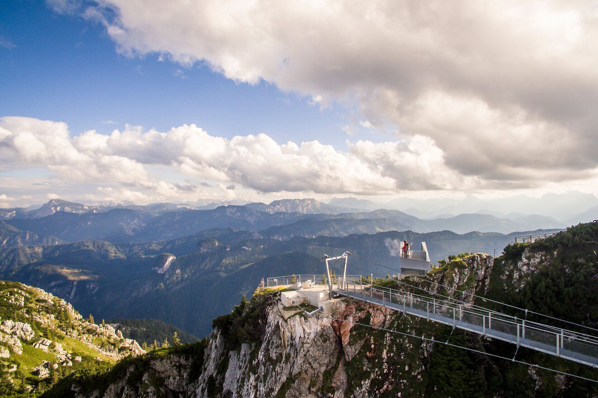 Die majestätischen Berge erheben sich unter einem strahlend blauen Himmel, während sanfte Wolken über die Gipfel ziehen. Wanderer genießen die atemberaubende Aussicht auf die umliegenden Täler und die unberührte Natur, die zu Erkundungen einlädt.