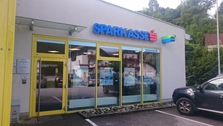 Eingang einer Sparkasse-Filiale mit gelbem Rahmen und Glast&uuml;ren.