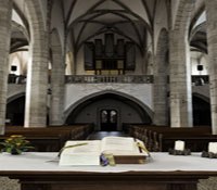 Innenansicht einer Kirche mit Altar und Orgel im Hintergrund.