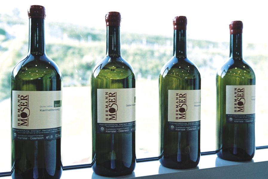 Vier Weinflaschen vom Weingut Hermann Moser auf einer Fensterbank.