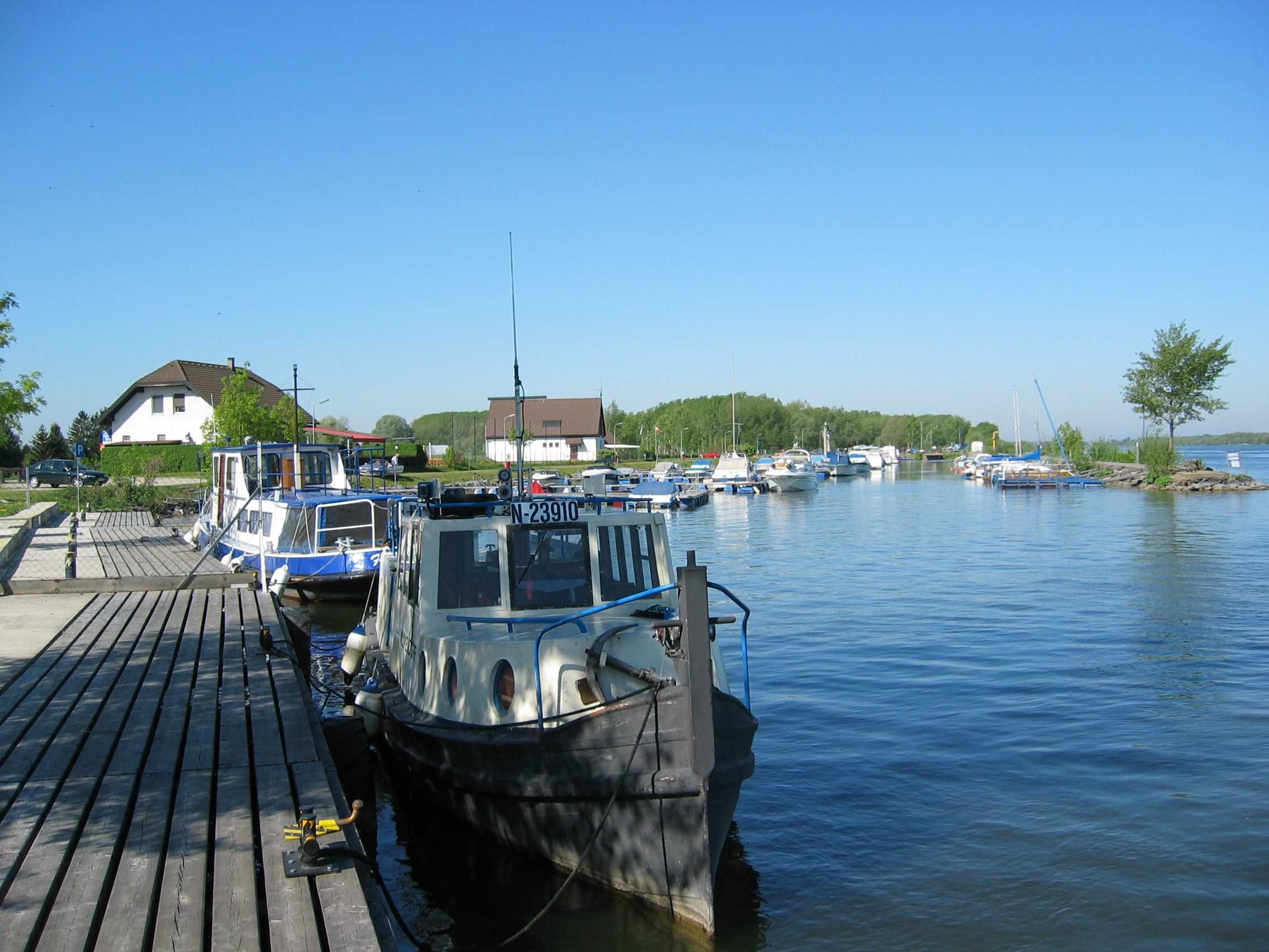 Boote an einem Steg in einem ruhigen Hafen mit blauem Himmel.