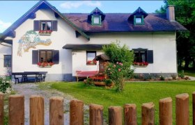 Ein traditionelles Haus mit Blumen an den Fenstern und einem Holzzaun im Vordergrund.