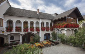 Traditionelles Geb&auml;ude mit Arkaden und Blumenk&auml;sten.