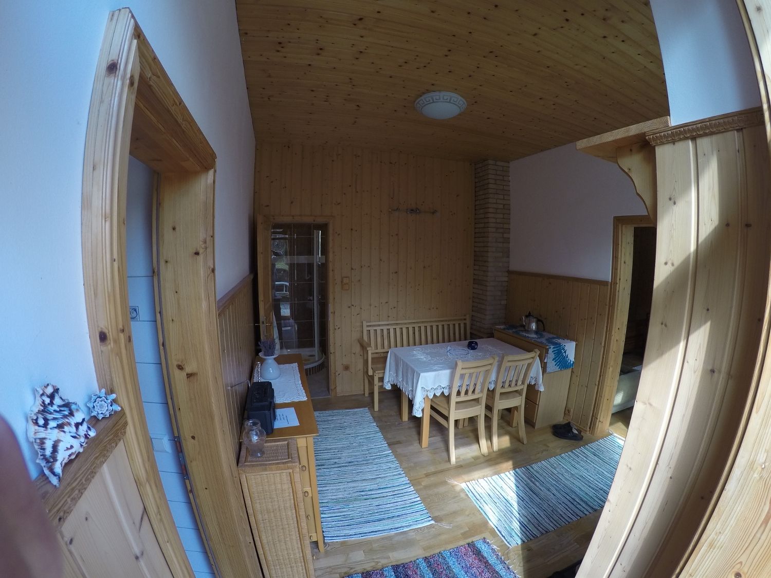 Esszimmer mit Holzwänden, Tisch und Stühlen, Teppichen und Dekorationen.