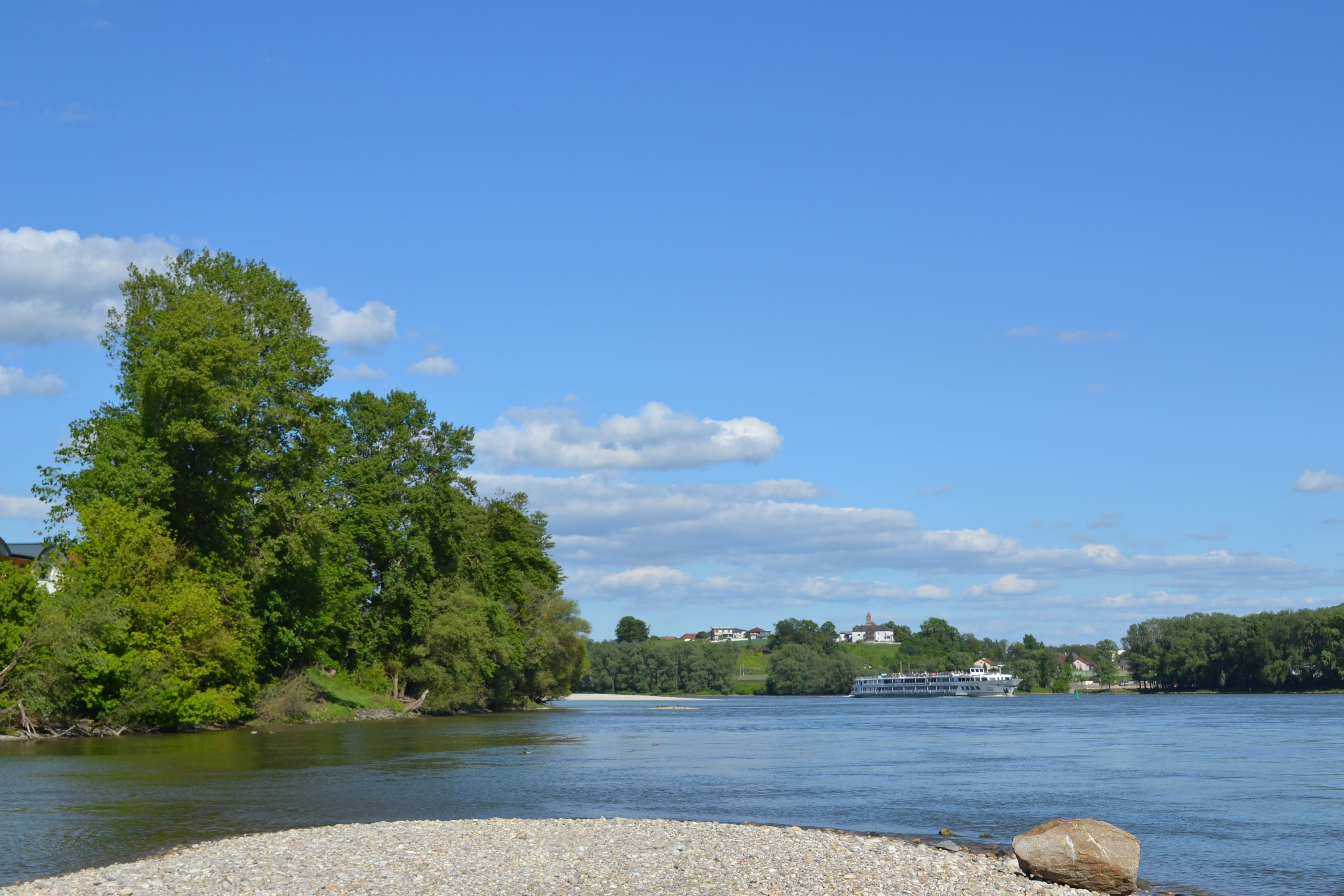 Flusslandschaft mit Bäumen und einem Schiff auf der Donau.