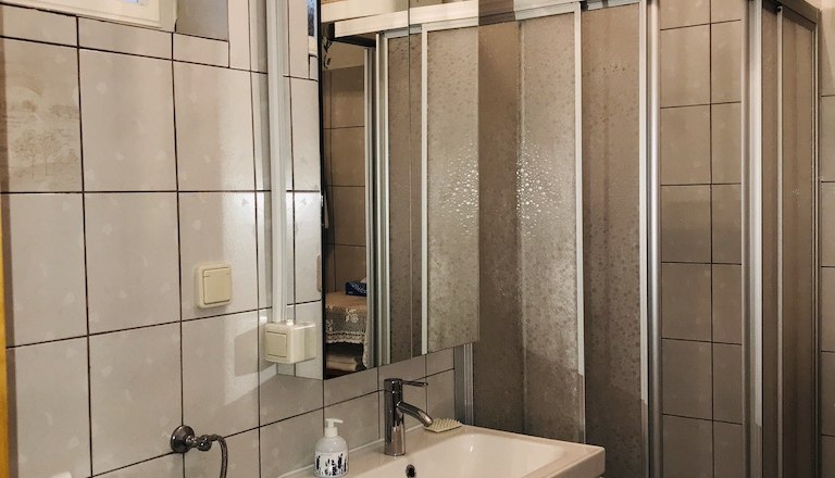 Badezimmer mit Dusche, Waschbecken und Fliesen.