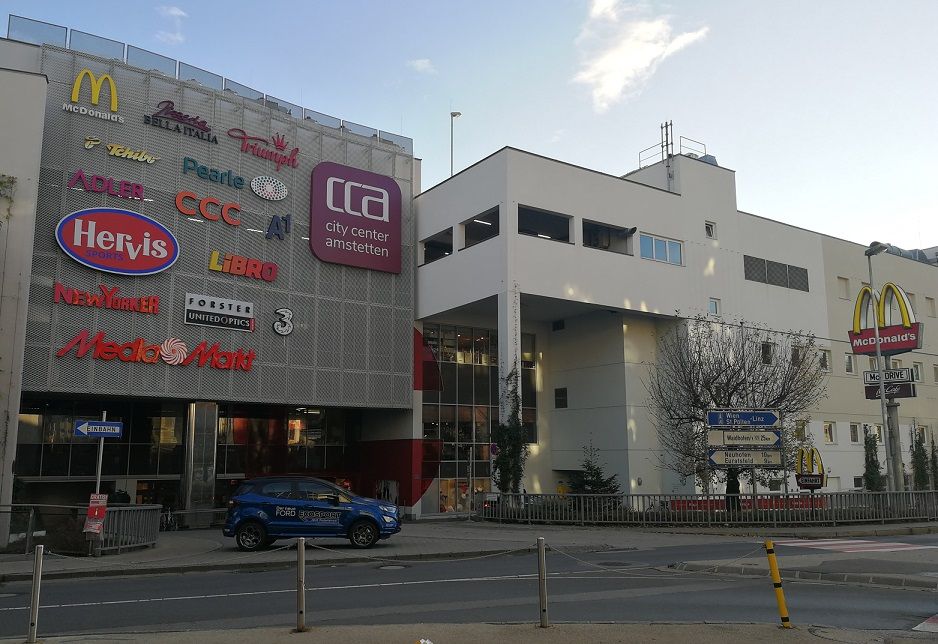 Einkaufszentrum City Center Amstetten mit Logos von Geschäften und McDonald's Schild.