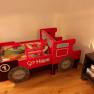 Rotes Spielzeugbett in Form einer Lokomotive mit Spielzeugeisenbahn.