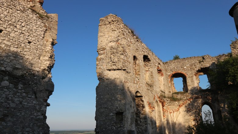 Ruinen der Burgruine Falkenstein bei Sonnenuntergang mit blauem Himmel.