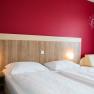 Schlafzimmer mit Doppelbett und roter Wand