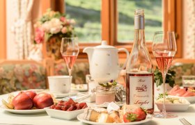 Frühstückstisch mit Obst und Käse und einer Flasche Frizzante