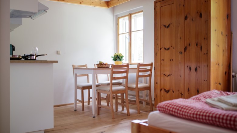 Innenansicht einer gem&uuml;tlichen Ferienwohnung mit Holzm&ouml;beln, Esstisch und Bett.