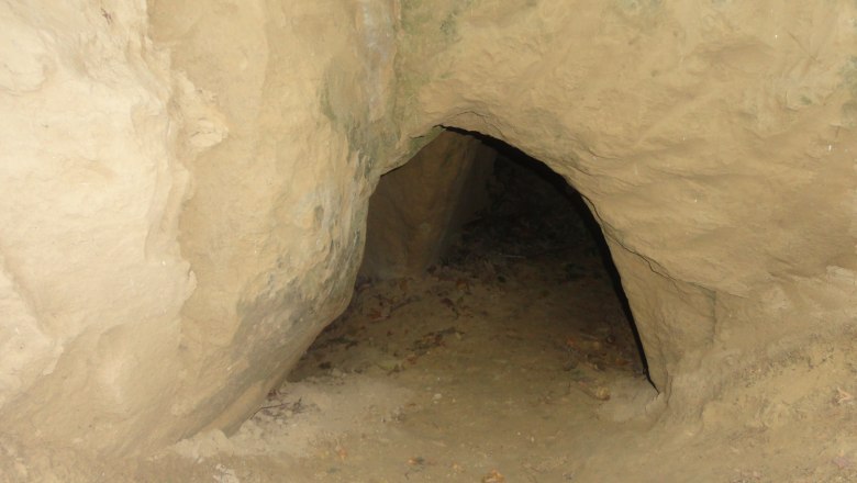 Eingang zu einer kleinen H&ouml;hle in sandigem Gestein.