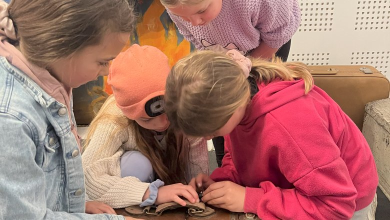 3 Kinder versuchen eine Koffer zu öffnen