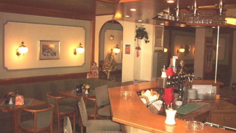 Innenansicht eines gemütlichen Cafés mit Holztresen und Sitzbereichen.