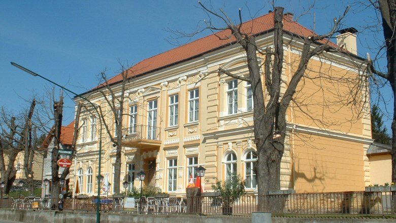 Gelbes Geb&auml;ude mit rotem Dach und kahlen B&auml;umen davor.
