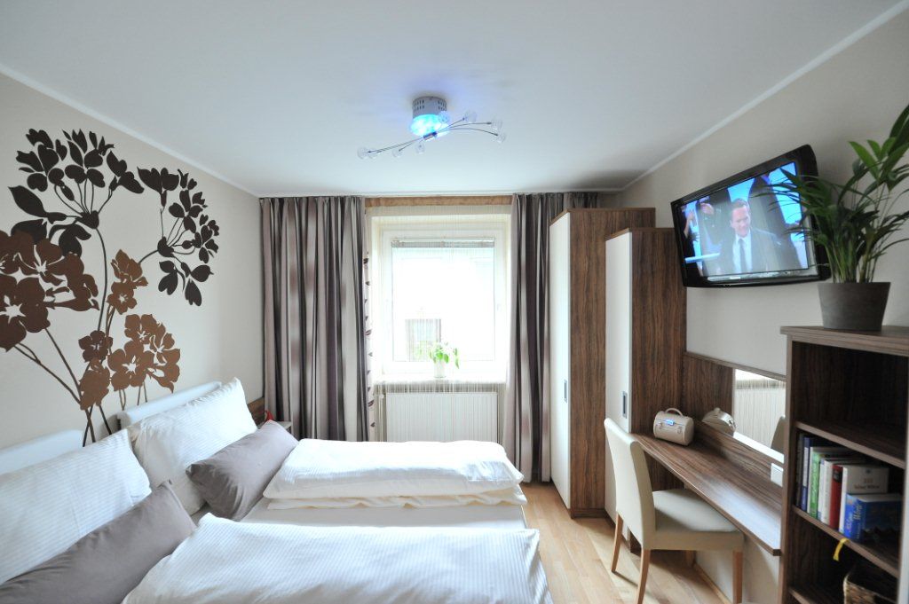 Ein modernes Schlafzimmer mit Doppelbett, Wanddekoration, Schreibtisch, Fernseher und Pflanzen.