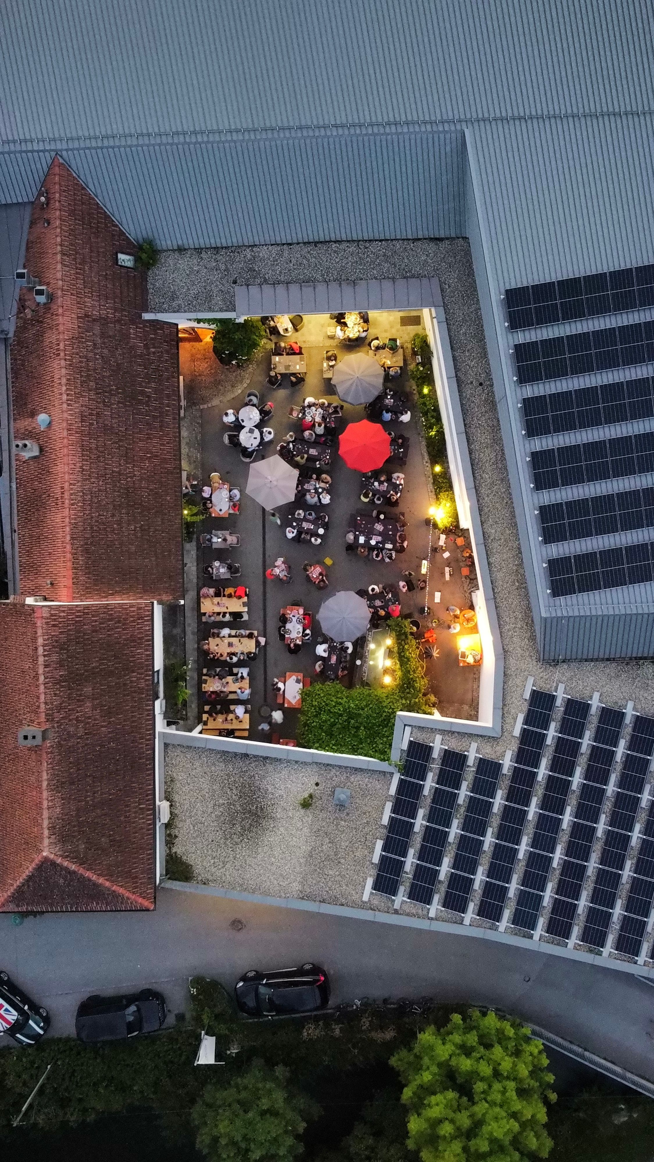 Luftaufnahme eines Weinguts mit Tischen und Sonnenschirmen im Innenhof.