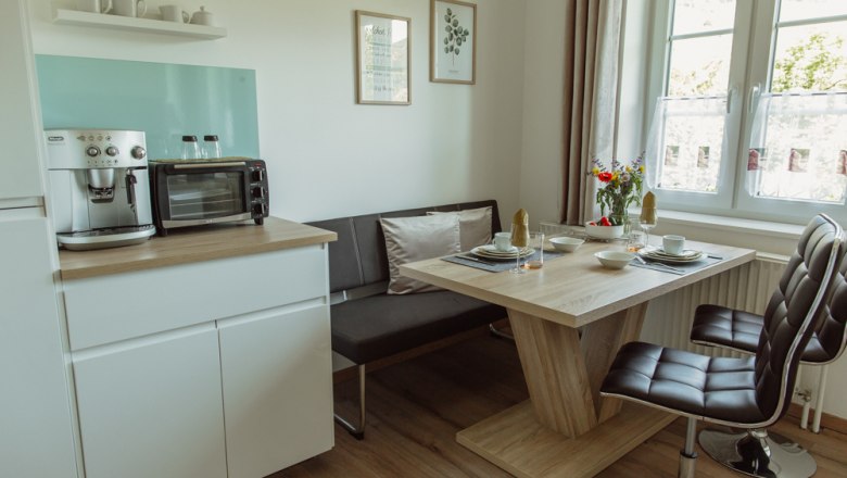 Moderne Küche mit Esstisch, Stühlen und Kaffeemaschine.