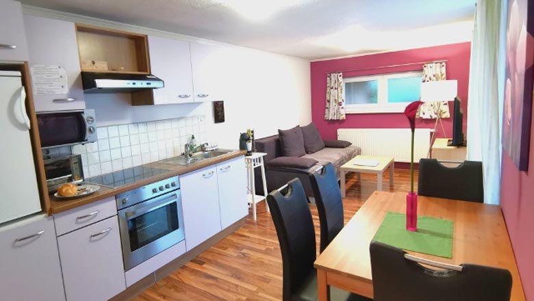 Innenansicht eines modernen Apartments mit Küche, Esstisch und Sofa.