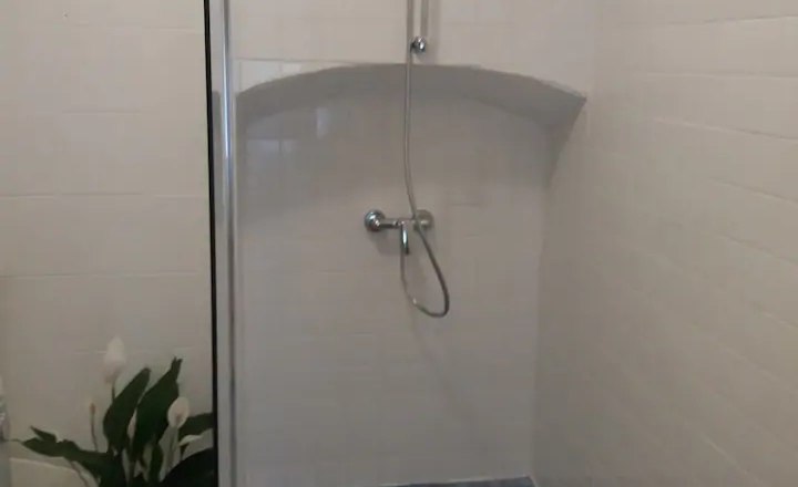 Moderne Dusche mit blauen Fliesen und wei&szlig;en W&auml;nden.