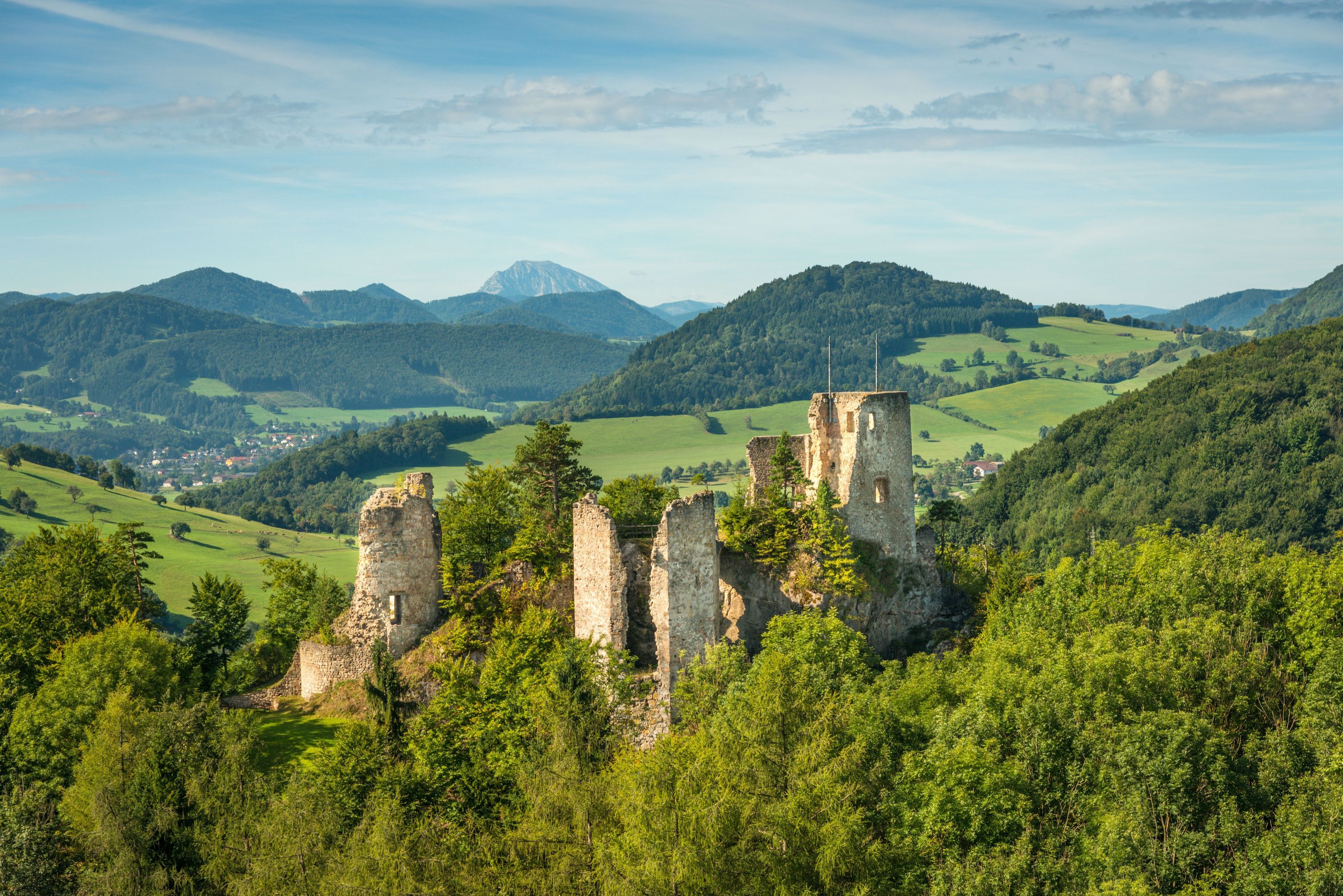 Ruine Rabenstein inmitten grüner Hügel und Wälder.