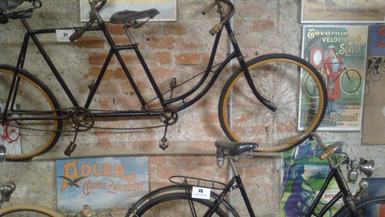 Alte Fahrr&auml;der und Vintage-Poster an einer Backsteinwand im Fahrradmuseum Schloss V&ouml;sendorf.