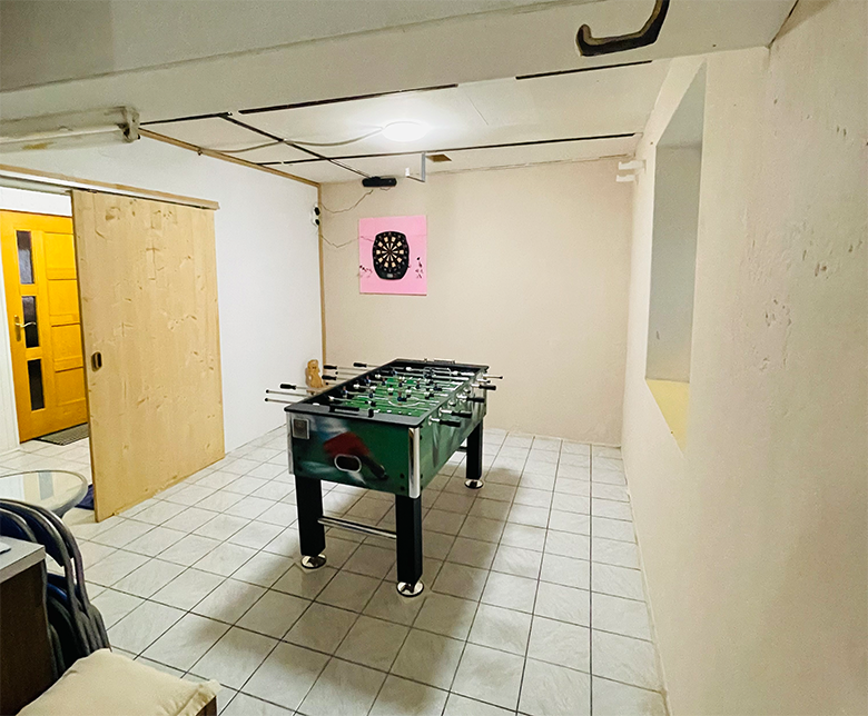 Ein Spielzimmer mit einem Tischkicker und einer Dartscheibe an der Wand.