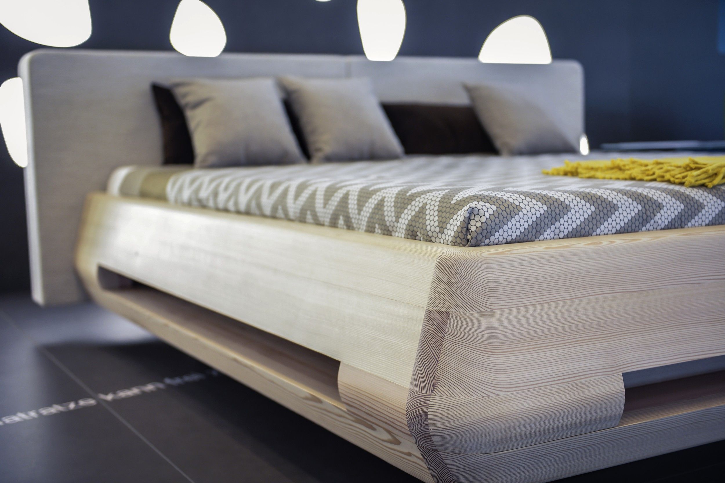 Modernes Bett mit Holzrahmen und gemustertem Bettbezug.