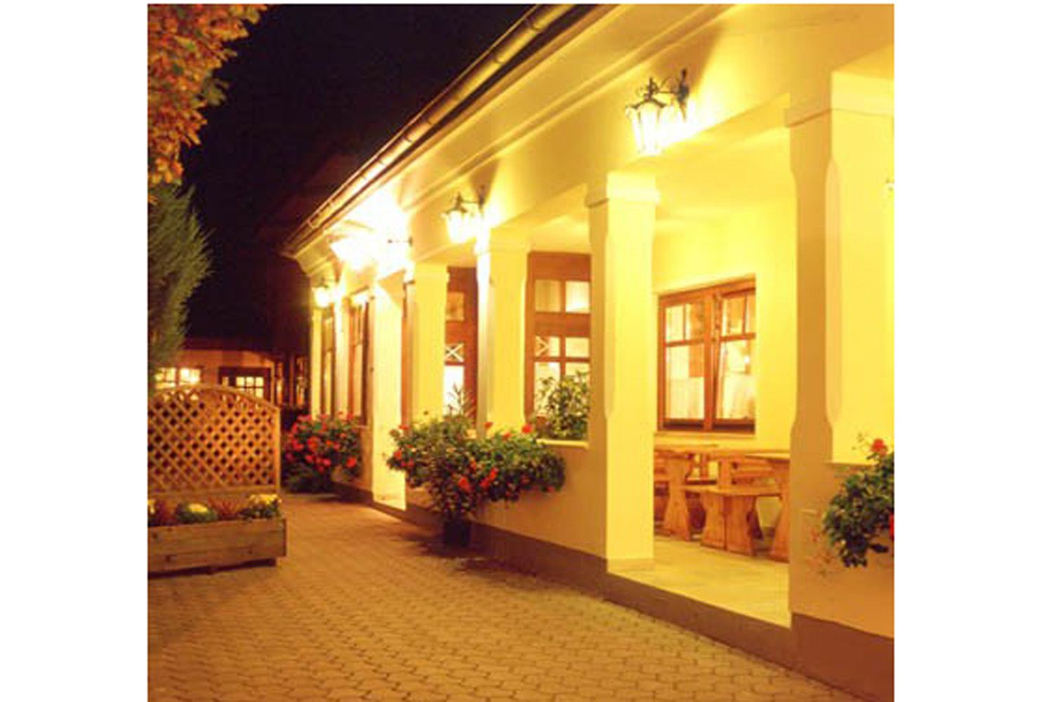 Beleuchteter Eingangsbereich eines traditionellen Gebäudes mit Säulen und Blumen.