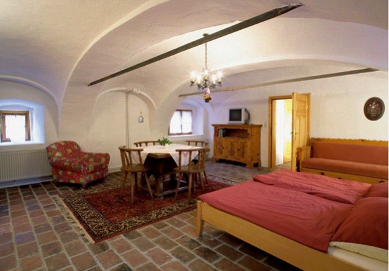 Gemütliches Zimmer mit Holzmöbeln, Doppelbett, Esstisch und Fernseher.