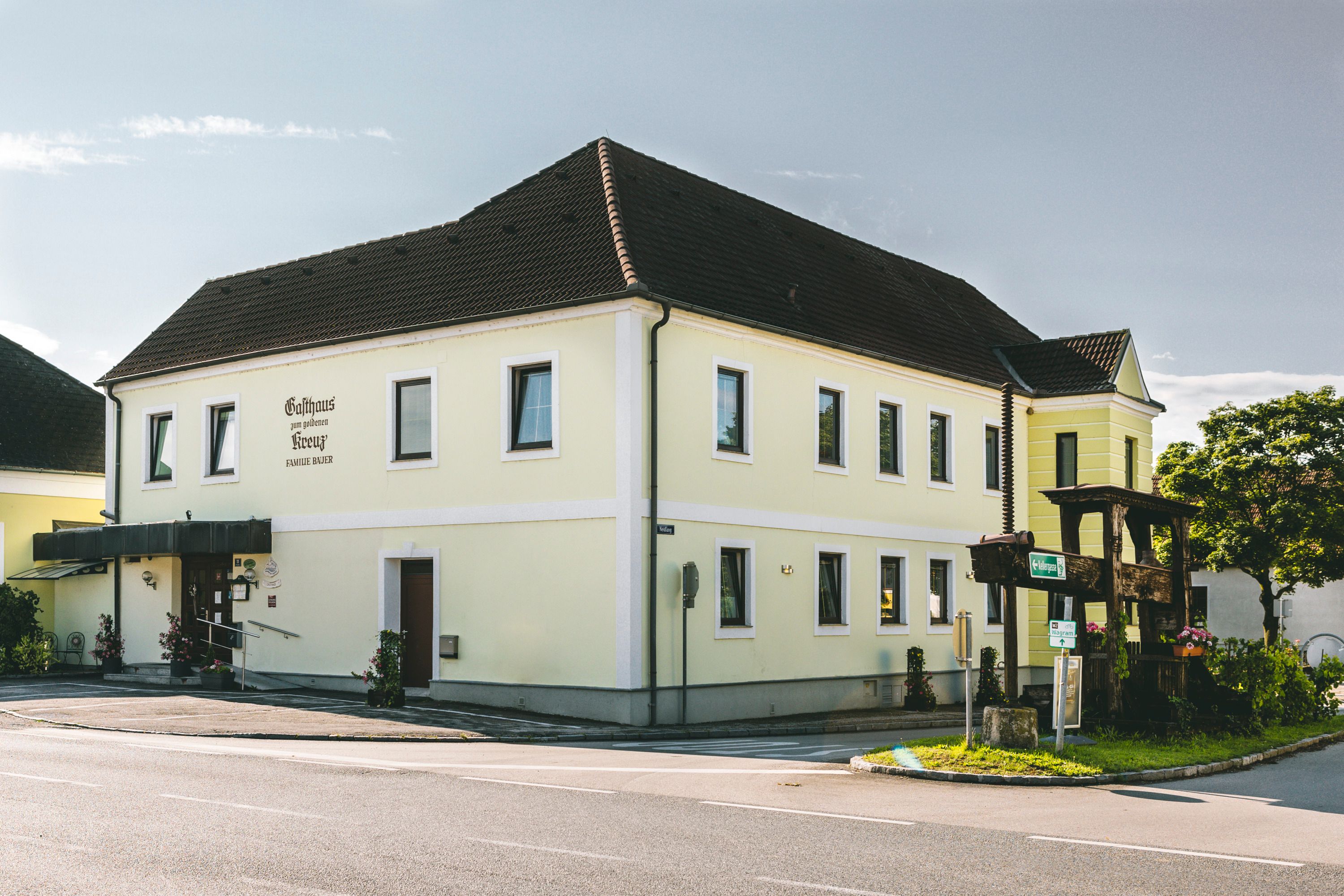 Gelbes Gasthaus an einer Straßenecke mit Blumendekoration.