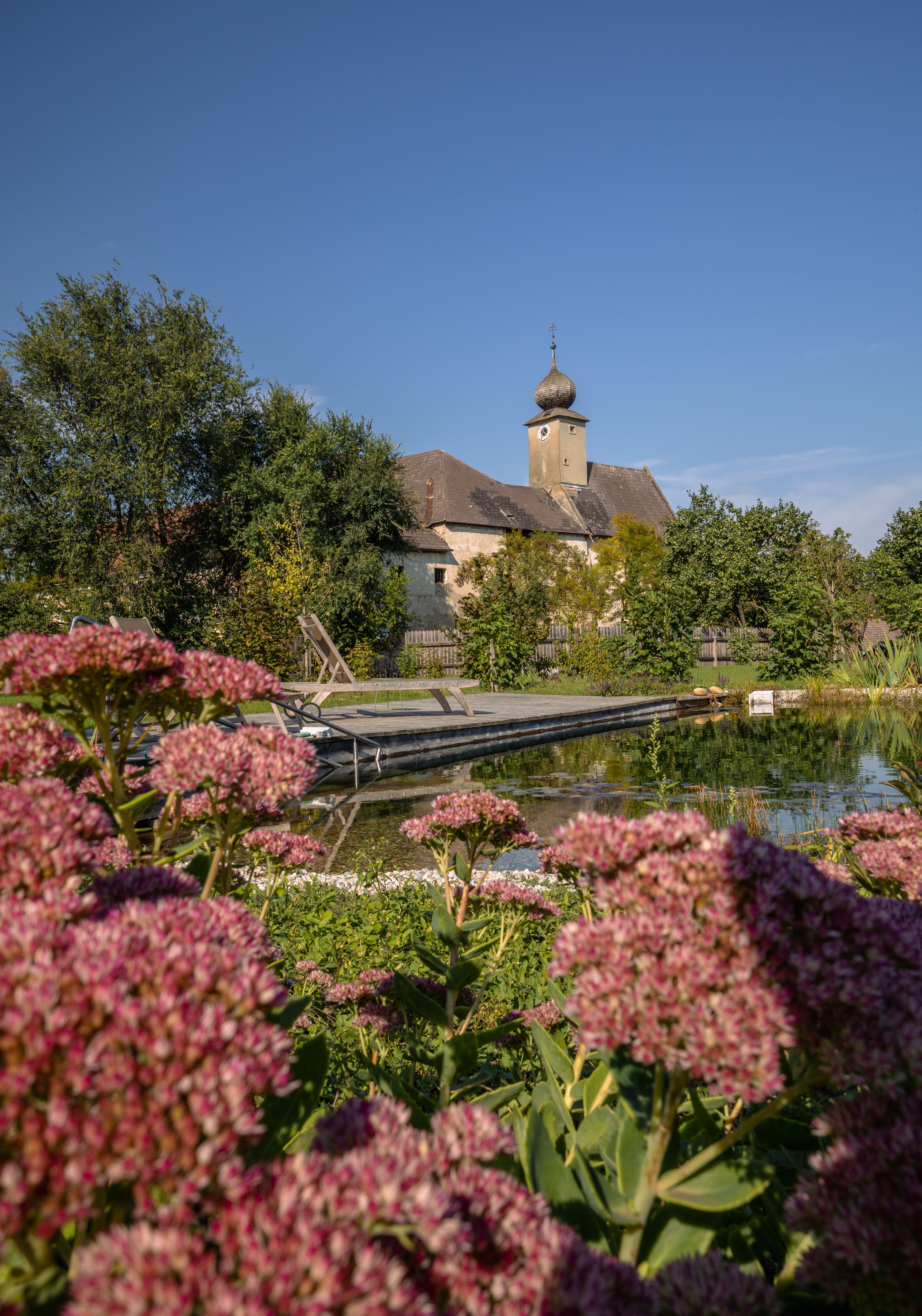 Schlafzimmer mit Gewölbedecke, Holzboden, Bett, Sessel, Kommode und Fellteppich.