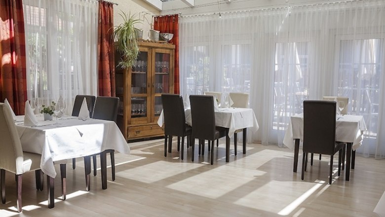 Innenansicht eines hellen Restaurants mit gedeckten Tischen und St&uuml;hlen.