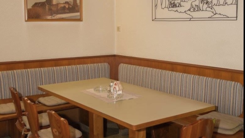 Gemütliche Sitzecke in einem Gasthof mit Holzmöbeln und Wanddekorationen.