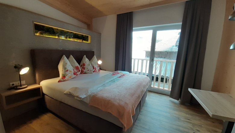 Gem&uuml;tliches Schlafzimmer mit Doppelbett, Holzboden und Balkon.