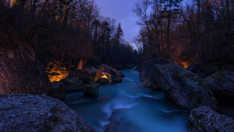 Nachtaufnahme der Erlaufschlucht mit beleuchteten Felsen und flie&szlig;endem Wasser.