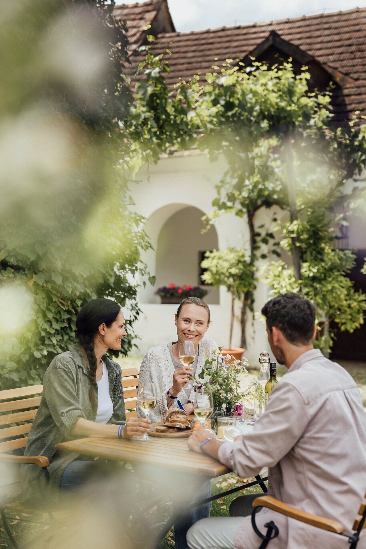 Inmitten der sanften Hügel des Weinviertels genießen Freunde eine gesellige Weinverkostung. Umgeben von üppigem Grün und blühenden Pflanzen, stoßen sie fröhlich mit Gläsern an und lassen sich von regionalen Köstlichkeiten verwöhnen. Die Atmosphäre ist entspannt und einladend, perfekt für einen unvergesslichen Tag im Weinfrühling.