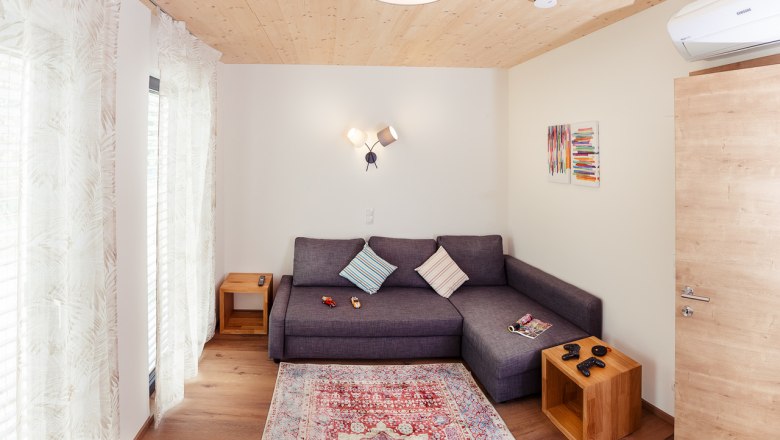 Modernes Wohnzimmer mit grauem Sofa, Holzboden und bunter Wandkunst.