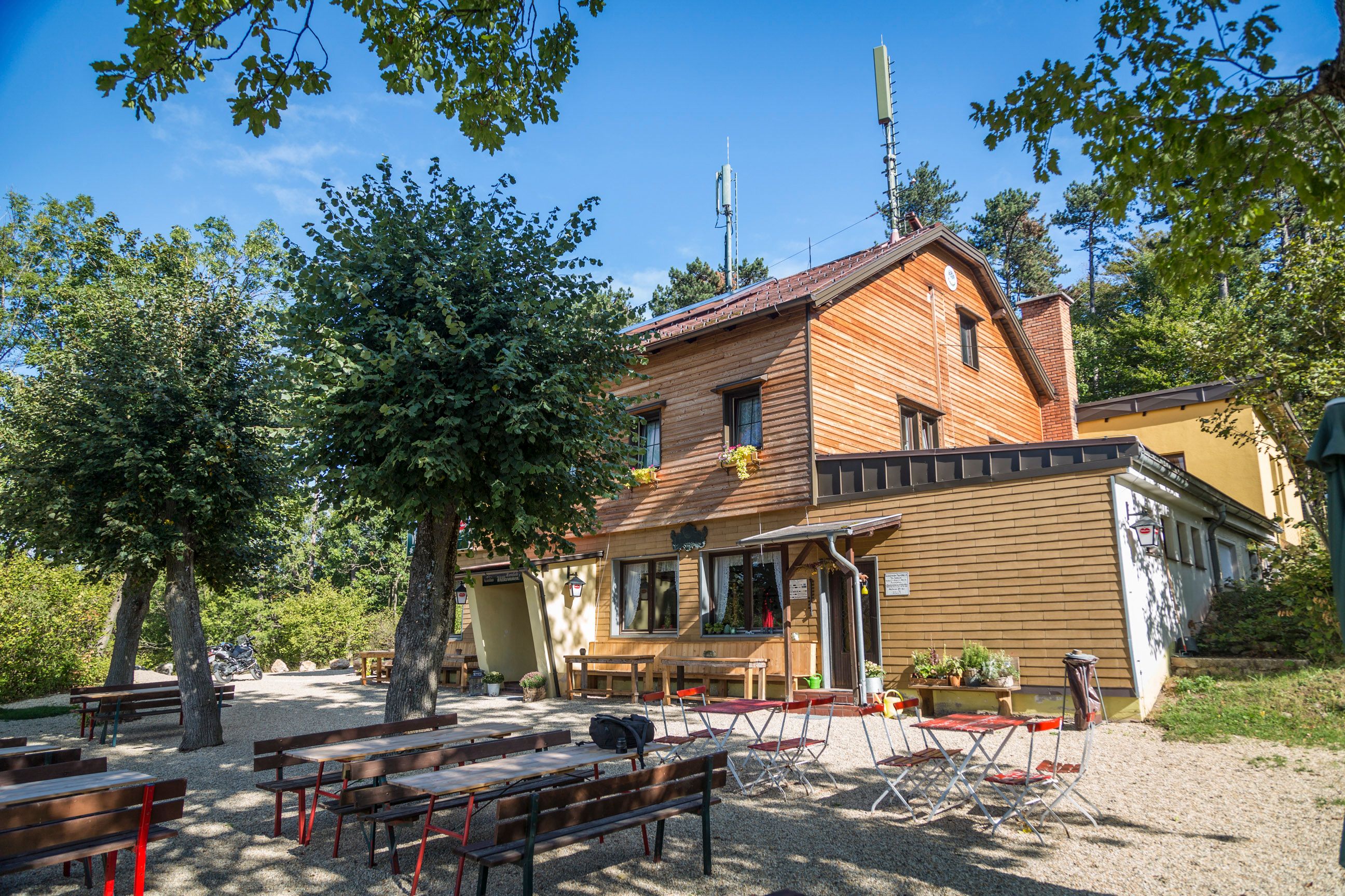 Holzhaus mit Biergarten im Freien, umgeben von Bäumen.