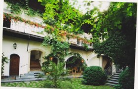 Ein grüner Innenhof mit Pflanzen und einem zweistöckigen Gebäude mit Balkonen.