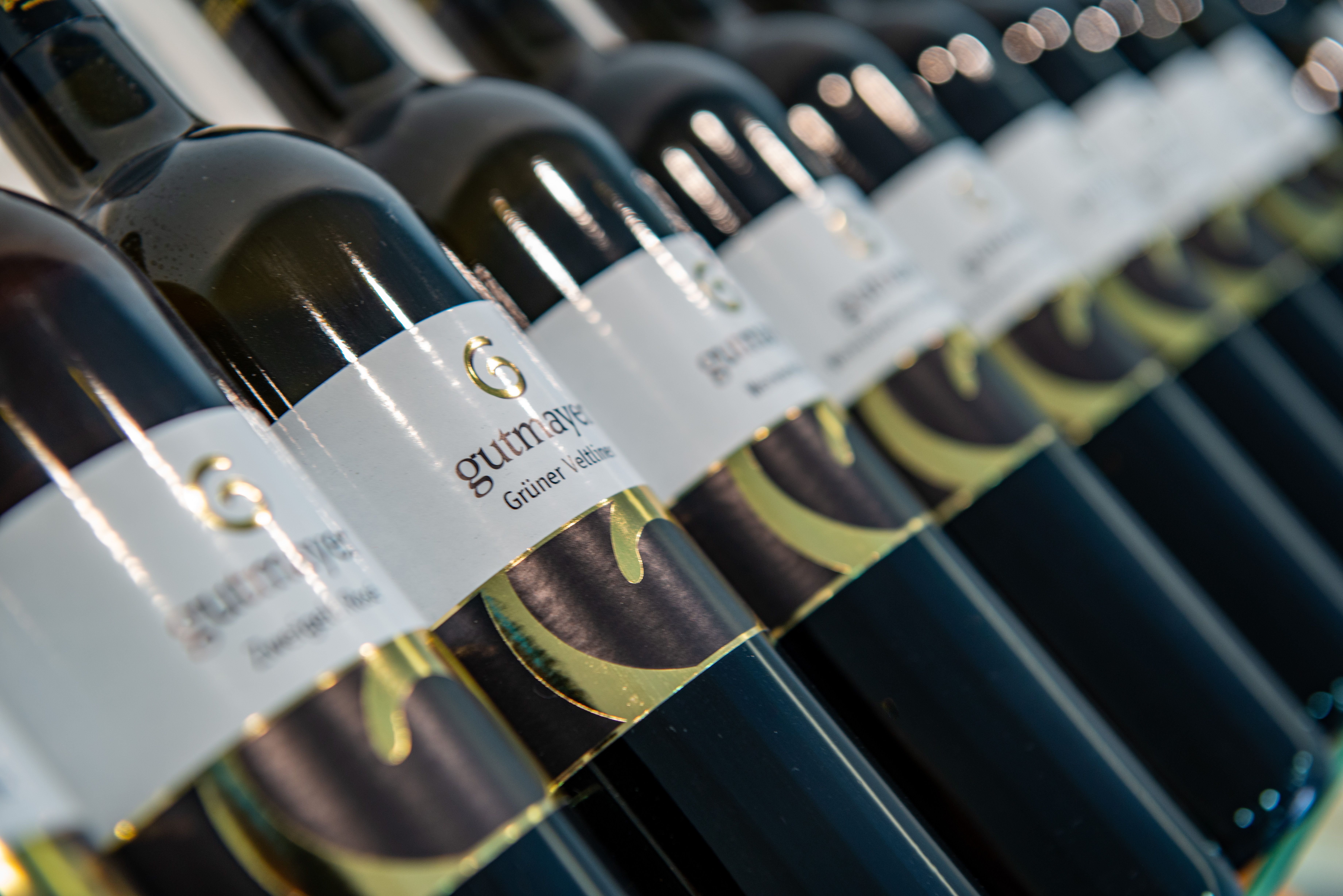 Nahaufnahme von Weinflaschen mit dem Etikett 'Gutmayer Grüner Veltliner'.