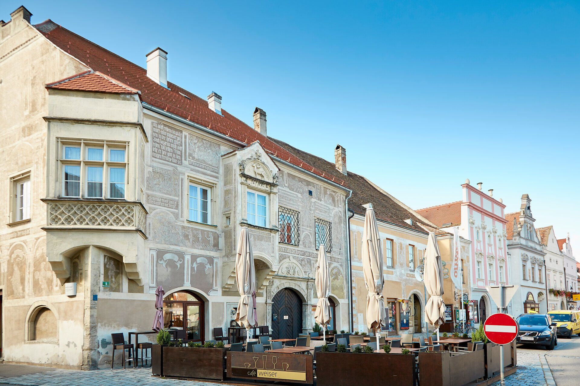 Historische Gebäude in Eggenburg mit verzierten Fassaden und einem Straßencafé im Vordergrund.