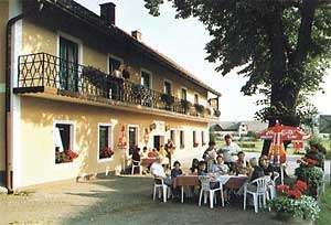 Gasthof - Pension "Zur Linde", © Gasthof - Pension "Zur Linde" Ein Gasthof mit Terrasse, auf der Menschen an Tischen sitzen, umgeben von Sonnenschirmen und Blumen.