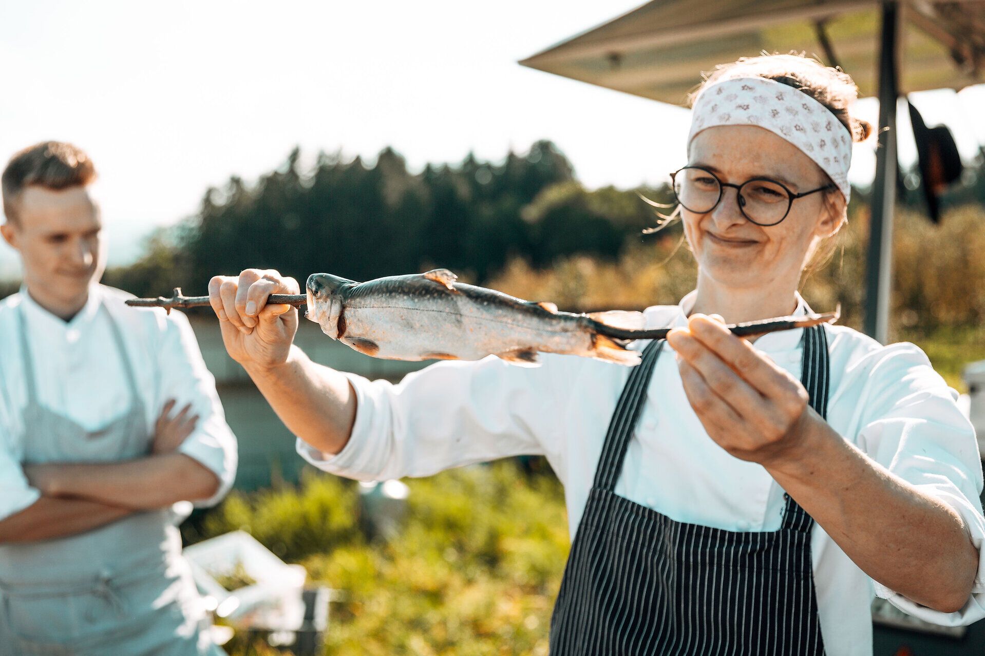 Inmitten der malerischen Landschaft des Mostviertels wird frischer Fisch auf kreative Weise zubereitet. Die Atmosphäre ist lebhaft und einladend, während die Köchin stolz ihr handwerkliches Geschick präsentiert. Ein unvergessliches Erlebnis für alle Feinschmecker und Naturliebhaber.