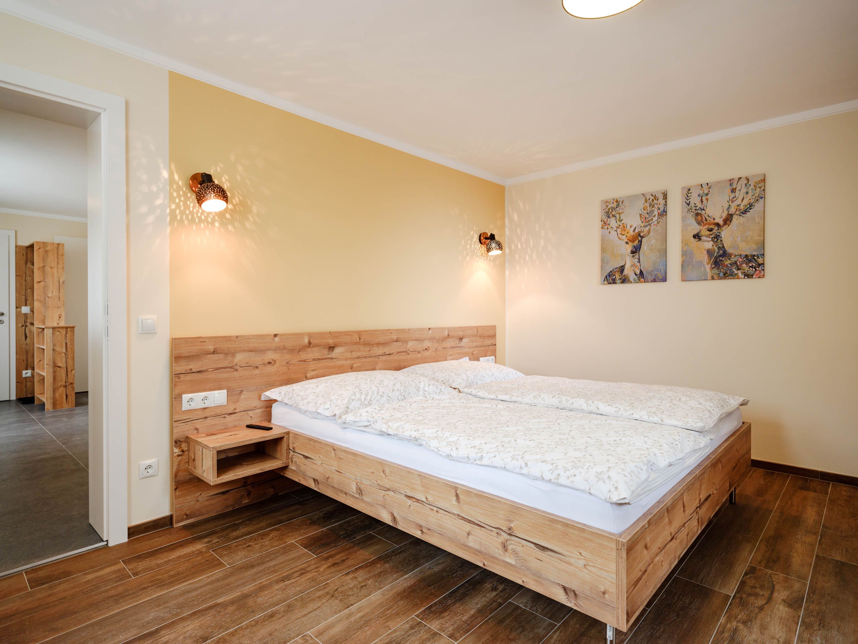 Gemütliches Schlafzimmer mit Holzbett und Hirschbildern an der Wand.